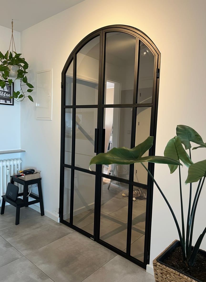 Seitliche Ansicht der Stichbogen-Drehtür mit Pflanze im Vordergrund