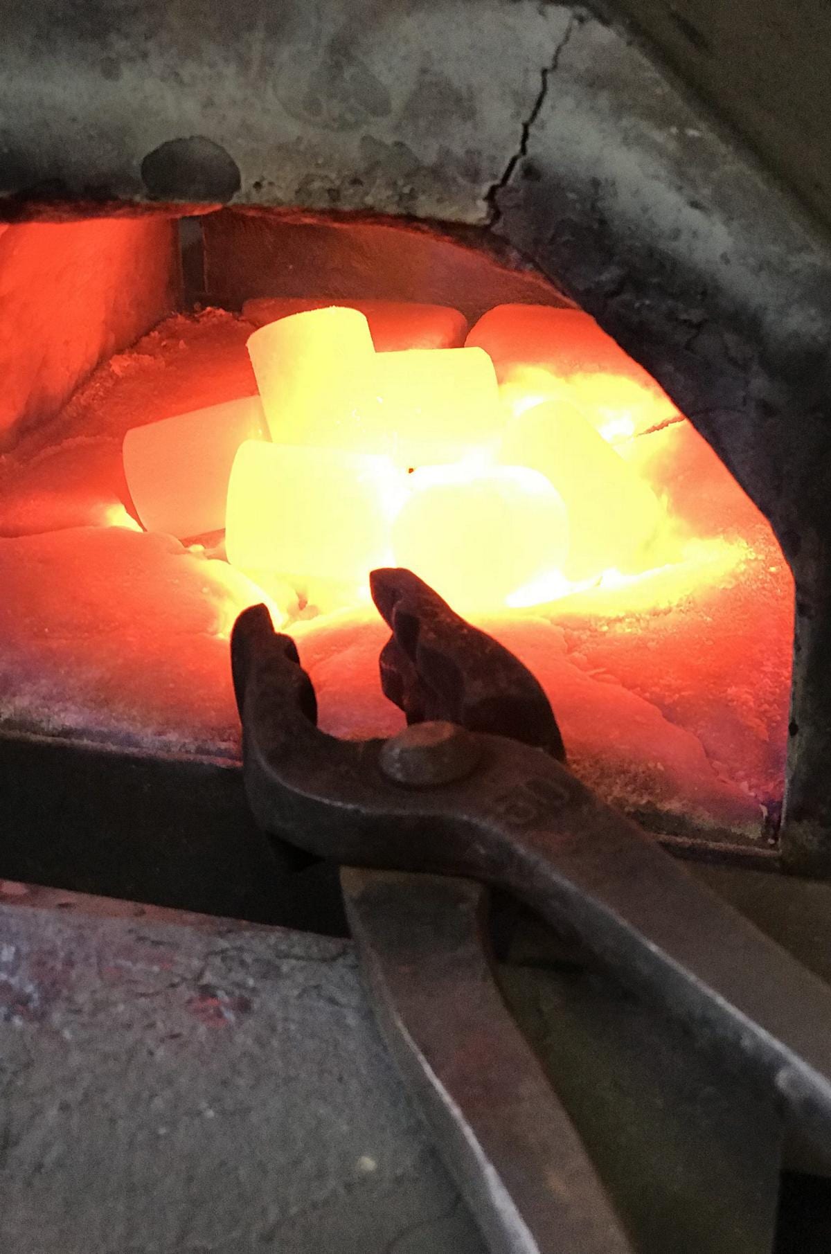 Glühende Eisenstücke im Schmiedeofen der Metallmanufaktur – traditionelle Metallbearbeitung